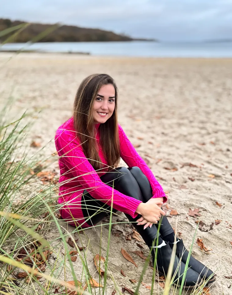 Aleksandra von Seelene im pinken Pullover am herbstlichen Strand, sie lächelt in die Kamera